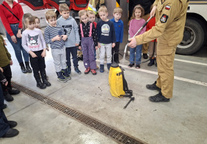 Strażak prezentuje dzieciom sprzęt strażacki