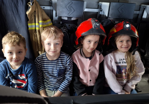 Czworo dzieci siedzi w wozie strażackim