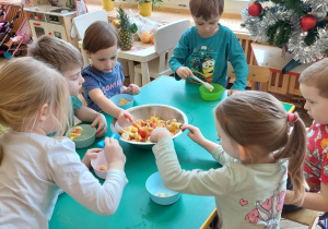 dzieci nakładają sałatkę owocową do miseczki