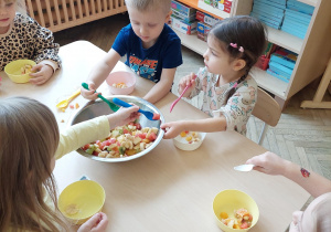 dzieci nakładają sałatkę owocową do miseczki