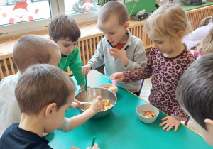 dzieci nakładają sałatkę owocową do miseczki