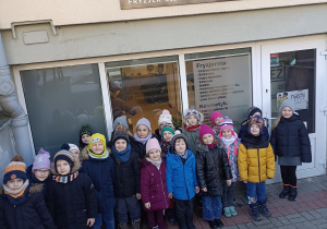 grupa dzieci stoi przed salonem fryzjerskim