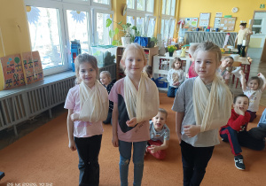 troje dzieci obwiązane chustą trójkątną