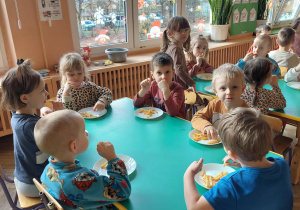dzieci siedzą przy stoliku i jedzą frytki