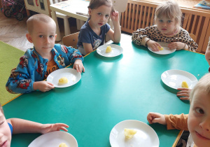 dzieci siedzą przy stoliku i jedzą ugotowanego ziemniaka