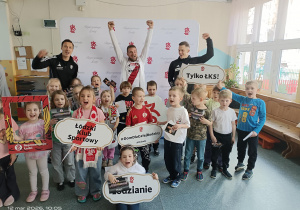 Dzieci z piłkarzami pozują do zdjęcia na tle baneru ŁKS