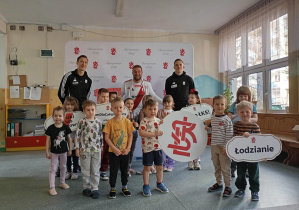 Dzieci pozują do zdjęcia z piłkarzami