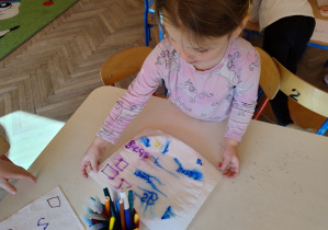 dziewczynka układa swój ręcznik papierowy na talerz z wodą i obserwuje rozmazane cyfry i kształty