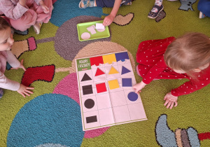 dziewczynka układa figurę geometryczną we właściwym miejscu kratownicy