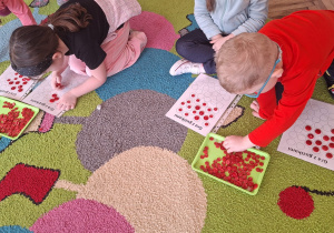 chłopiec bierze guzik z tacki a dziewczynka układa guziki na planszy