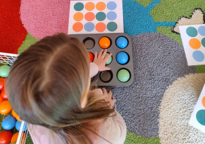 dziewczynka układa piłki według wzoru