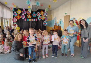 uczestnicy konkursu trzymają dyplomy z nagrodami i pozują do zdjęć z paniami na tle dekoracji i widowni