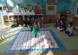 chłopiec stoi na macie do kodowania i układa kubeczki