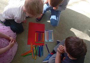 dzieci układają wzór z kolorwych patyczków