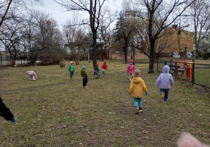 grupa dzieci sprząta okolice placu zabaw