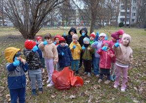 grupa dzieci stoi z workiem z odpadami