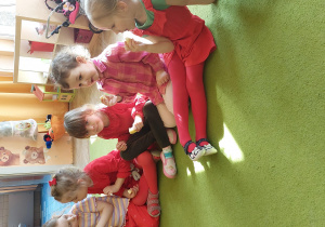 dzieci siedza na dywanie i jedzą jabłka