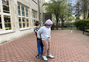 dwoje dzieci stoi tyłem do siebie