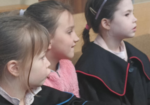 dwie dziewczynki w togach a jedna pośrodku bez togi