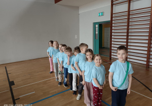 grupa dzieci w niebieskich koszulkach stoją jeden za drugim