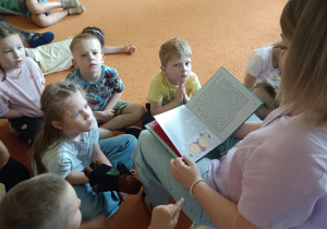 dzieci siedzą w kole i słuchają opowiadania czytanego przez mamę dziewczynki