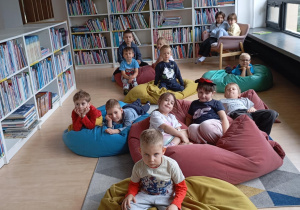 dzieci siedzą na pufach