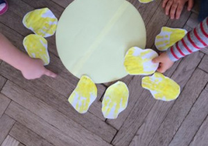 dzieci układają wycięte dłonie wokół żółtego koła