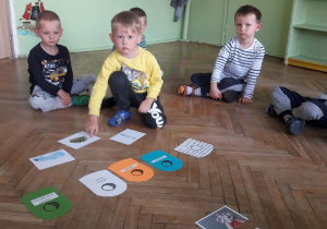 4 dzieci siedzi na podłodze w rozłożonymi obrazkami