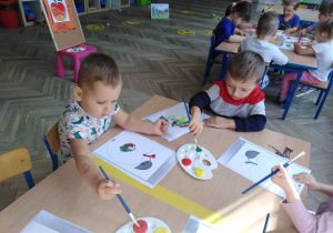 dwóch chłopców na pierwszym planie malują farbami