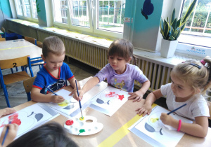troje dzieci maluje farbami