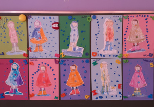 wystawa prac dzieci przedstawiająca postacie w kurtkach przeciwdeszczowych oraz padający deszcz