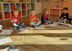 sześcioro chłopców siedzących na podłodze gra na marakasach i dzwonkach