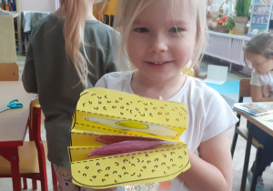 dziewczynka uśmiecha się i trzyma w rączkach papierowa kanapkę