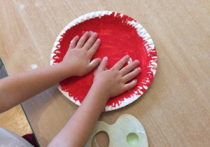 rączki dziecka na okrągłym czerwonym talerzyku
