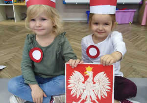 dwie dziewczynki trzymają godło polskie
