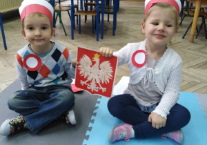 chłopiec i dziewczynka trzymają godło polskie