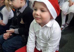 Chłopiec siedzi w czapce Mikołaja