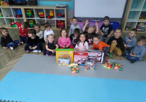 Dzieci siedzą w grupie z otrzymanymi prezentami