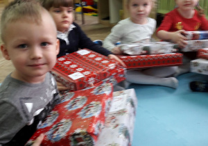 Dzieci siedzą w grupie i trzymają prezenty