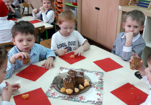 Dzieci siedzą przy stoliku i smakują poczęstunek