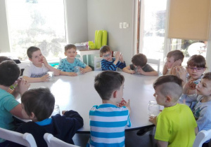 dzieci siedzą przy okrągłych stołach ze słoikami
