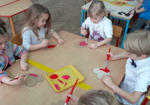 grupka dzieci malująca farbami serca na patyku