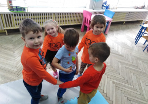4 dzieci w kole tańczy a w środku koła stoi chłopiec