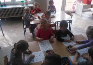 dzieci przy stole kolorują figury