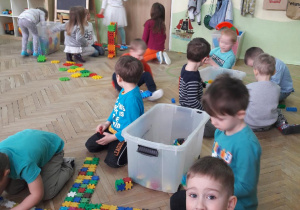 grupa dzieci buduje z klocków duże dinozaury