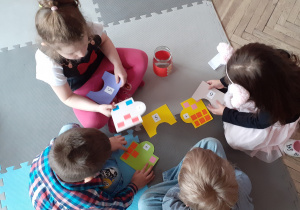 czworo dzieci układa puzzle matematyczne