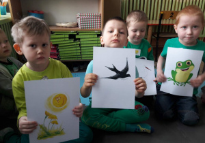 czworo dzieci trzymającymi obrazki ze zwiastunami wiosny