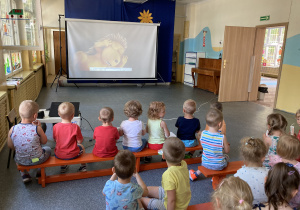 grupa dzieci ogląda bajkę na dużym ekranie