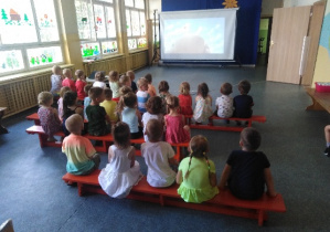 grupa dzieci ogląda bajkę na dużym ekranie