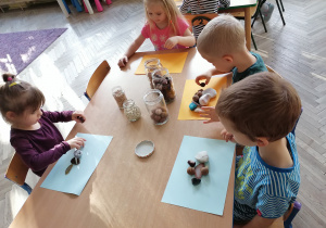 Dzieci przy stoliku wykonuja pracę artystyczną